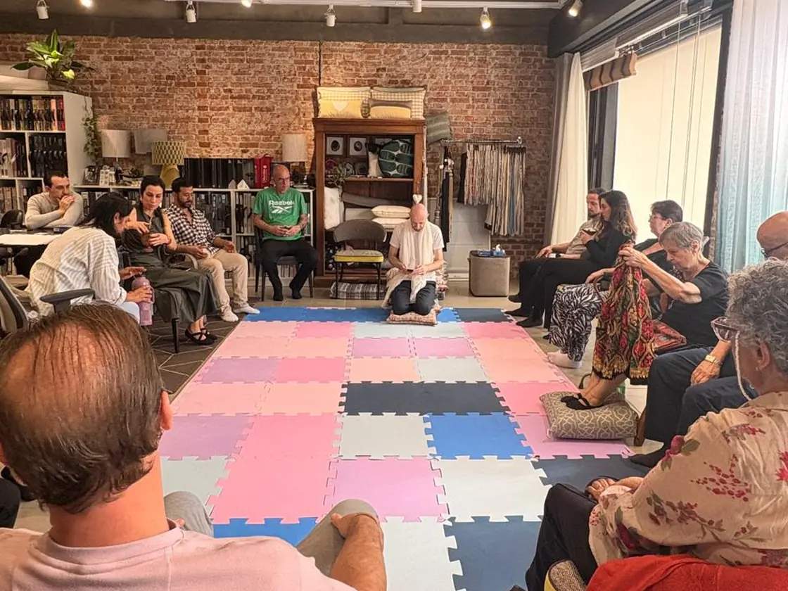 Grupo sentado em círculo em torno do tapete durante uma vivência, observando as gerações da família